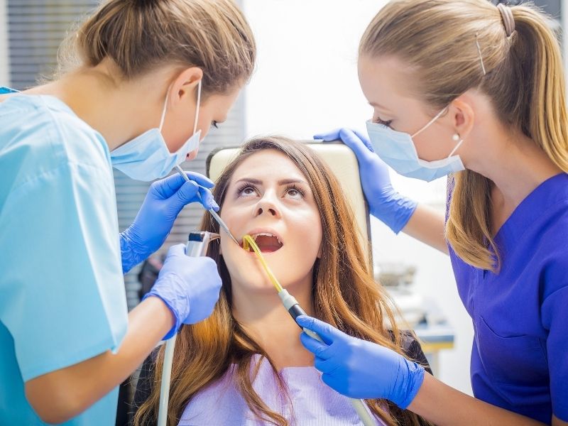 Dental team applying clear aligners or braces to a patient to correct alignment.