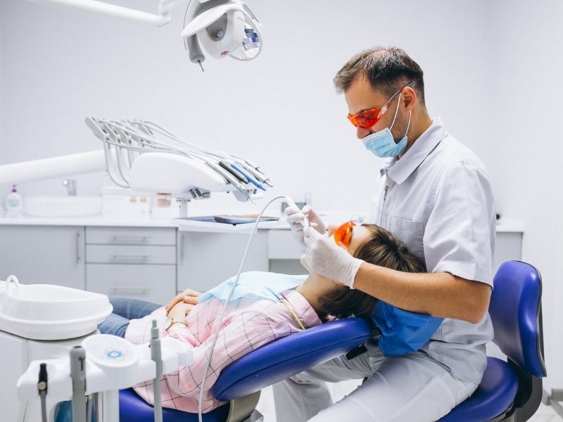 Dentist using protective eyewear and precision laser tools for oral surgery.